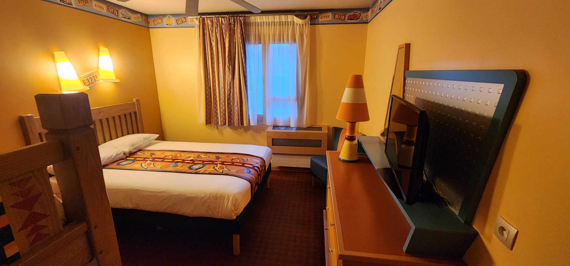 Our Cars themed room at Hotel Santa Fe featuring a queen bed accross from a dresser with a traffic cone lamp and flat screen TV