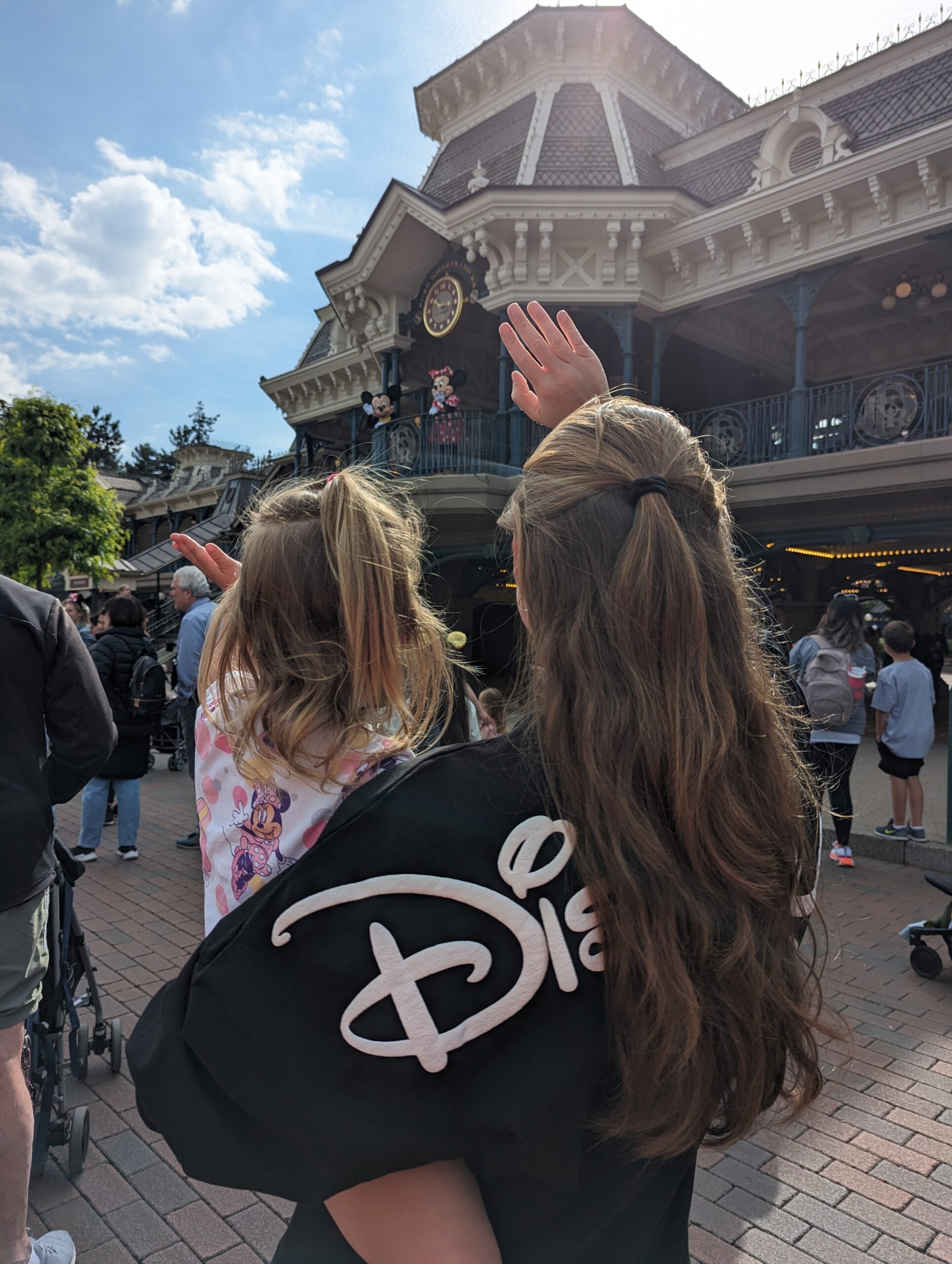 Me holding my daughter and waving at Mickey Mouse