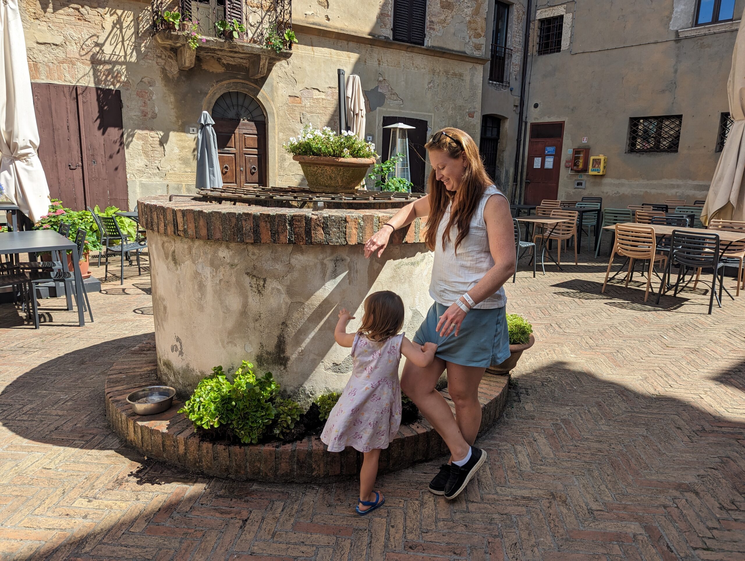 a mother and daughter standing at a well
