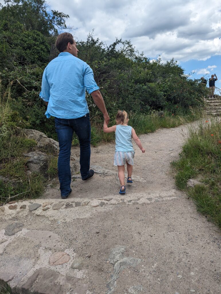 a father and daughter hiking on a gravel path