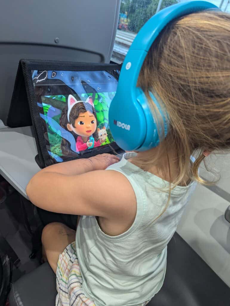 My toddler sitting on a train watching a show on her tablet