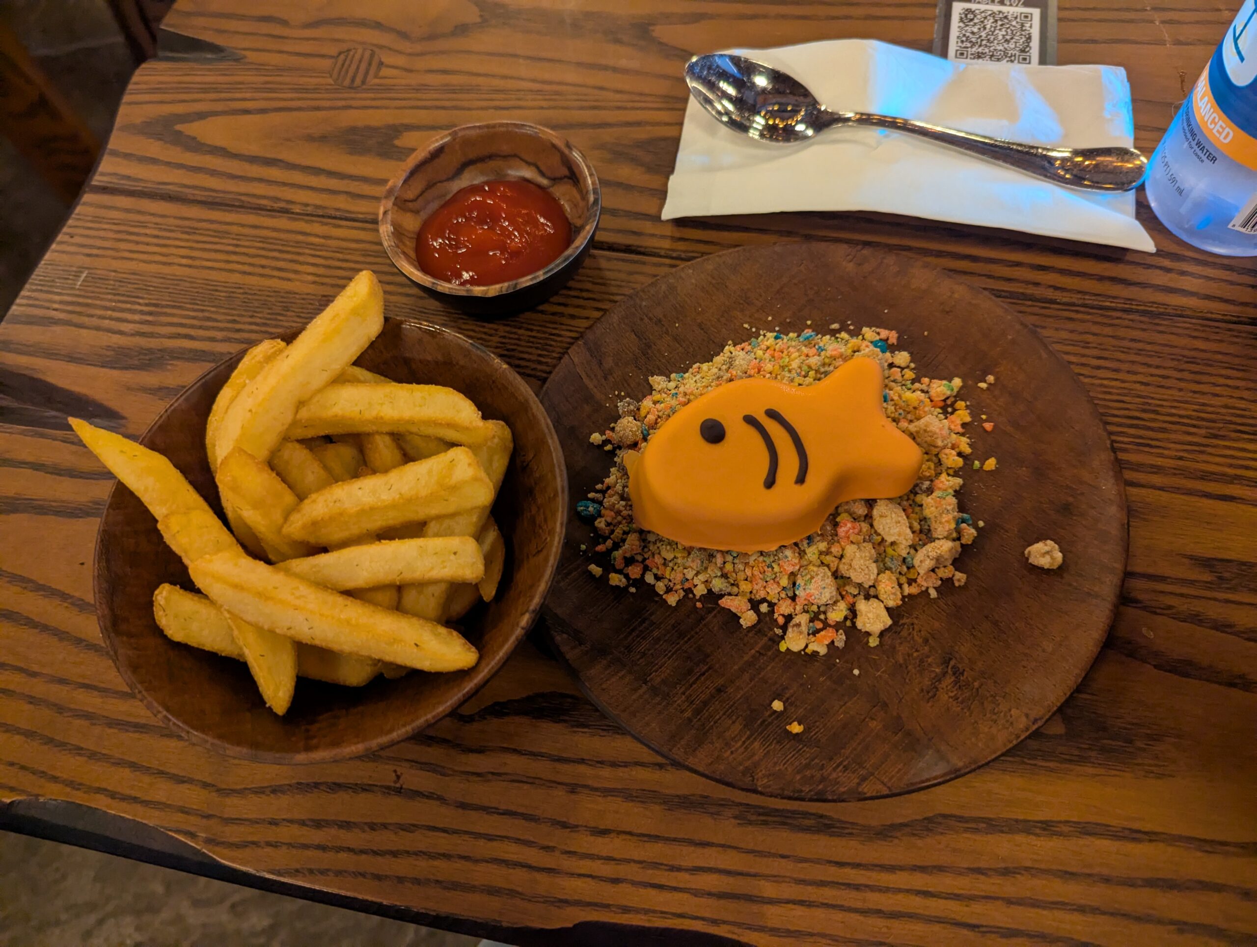 Lunch of french fries and chocolate mousse shaped like a gold fish on cereal crumbs from mead hall in isle of burke